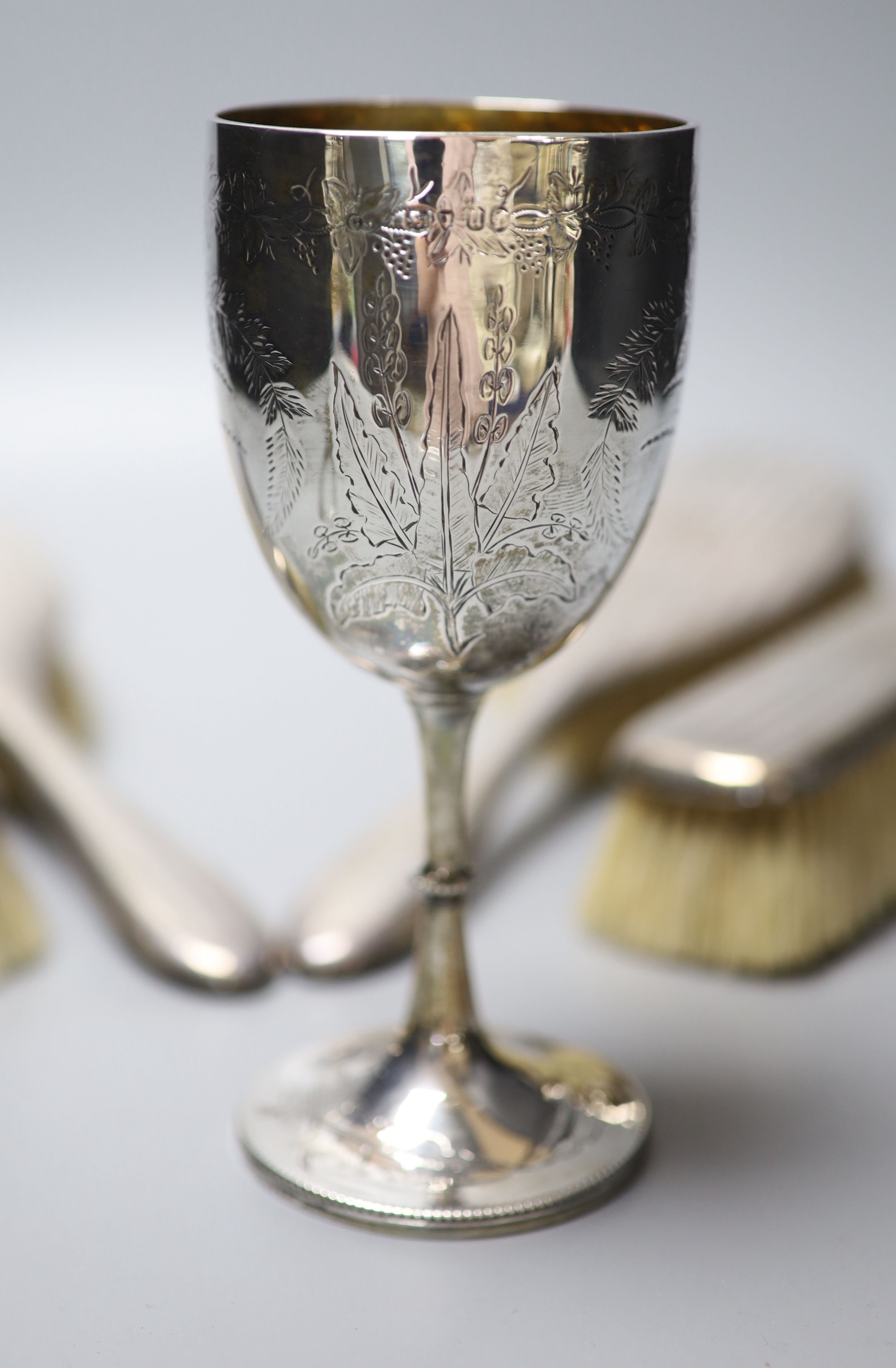 A Victorian engraved silver goblet, London, 1875, 6.3cm, a pair of silver sugar tongs and four silver mounted brushes.